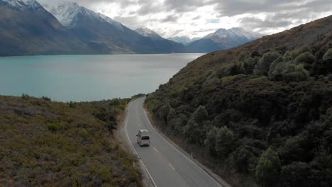 紐西蘭皇后鎮 (queensstown, new zealand) 的kwatipu湖沿岸的山脈上駕駛露營車,背景是新鮮的雪 - - 空中無人機