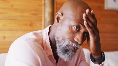 senior african american man spending time in log cabin and sitting on couch, slow motion