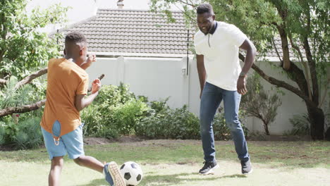 Un-Padre-Afroamericano-Juega-Al-Fútbol-Con-Un-Hijo-En-Un-Soleado-Patio-Trasero