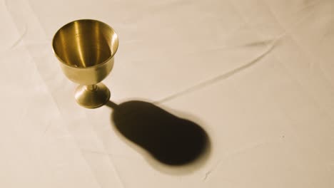 concepto religioso filmado con cáliz en el altar en un charco de luz
