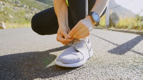 Senior-woman-tying-shoe-laces-on-a-road-at-countryside-4k