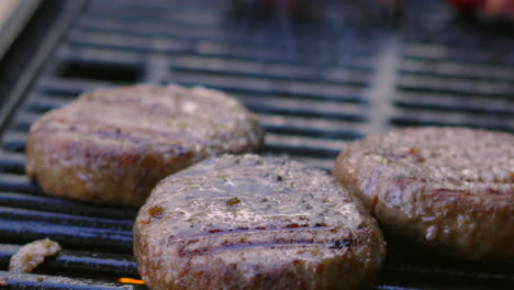 beef burgers being cooked on bbq grill with smoking flames below. high quality barbecue summer cooking food.