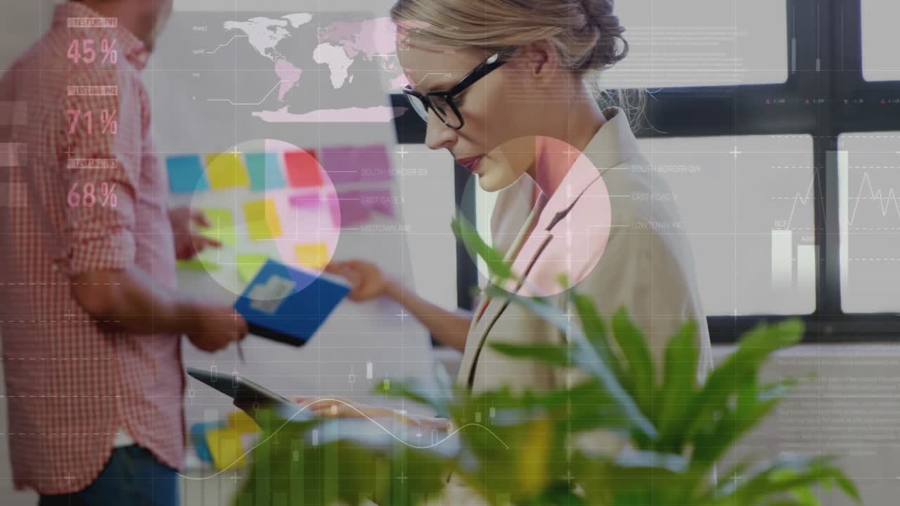 Mujer de mediana edad desplazándose en una tableta con compañeros de trabajo mientras los gráficos de datos empresariales aparecen para su revisión.