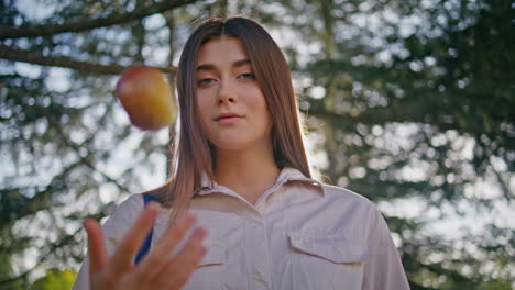 mujer contemplativa sosteniendo una manzana en el parque verde de primer plano. retrato modelo femenino