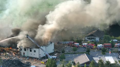 aftermath of the explosion due to propane leakage, fire and massive smoke in the air, firefighting trucks and engines at the explosion site, aerial view