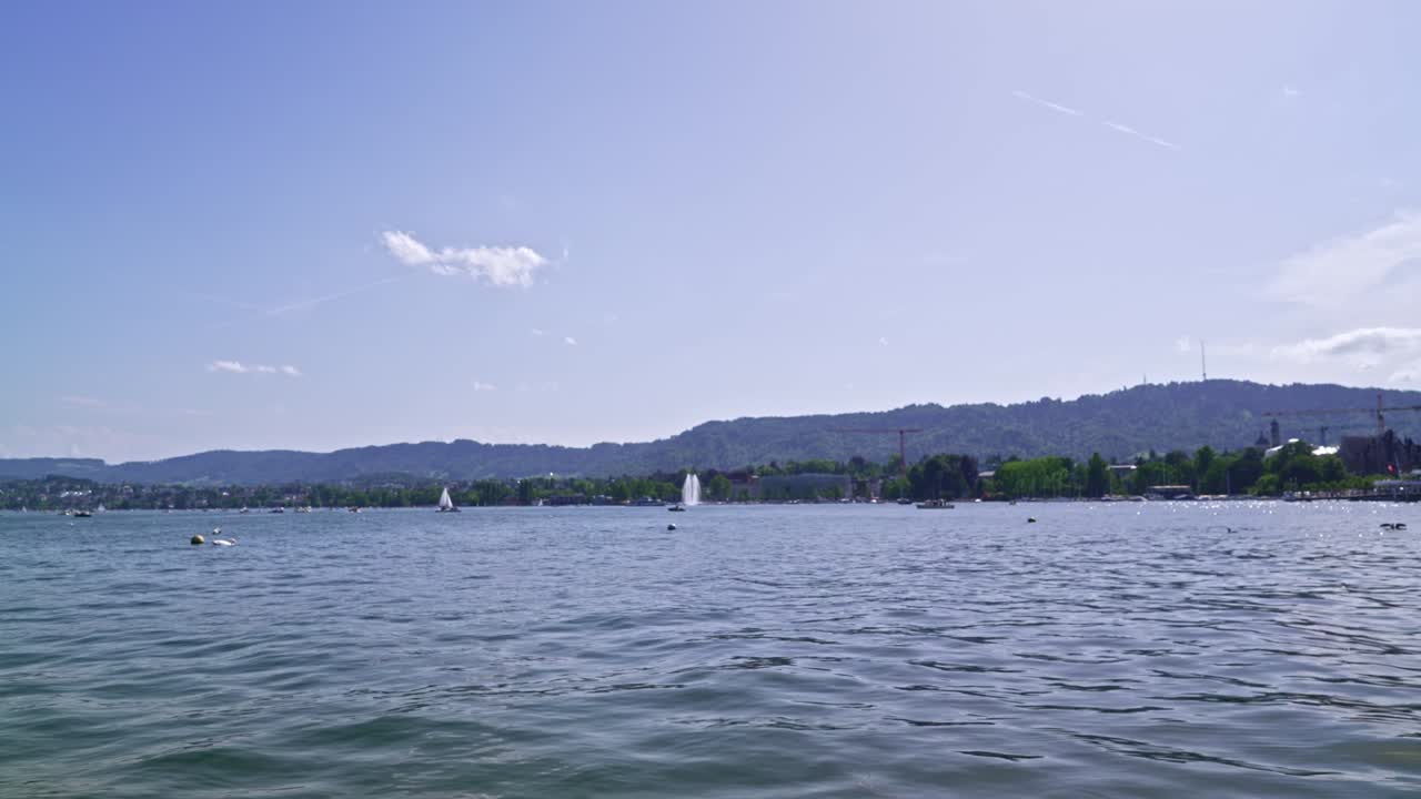 lago de zúrich con velero, fuente y aves marinas en un soleado día de primavera.