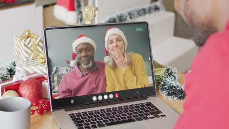 hombre afroamericano teniendo videoconferencia de navidad con una pareja diversa senior