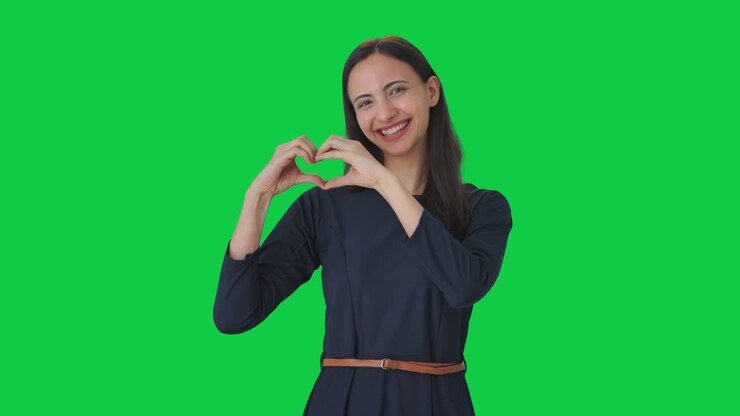 chica india feliz mostrando el signo del corazón pantalla verde