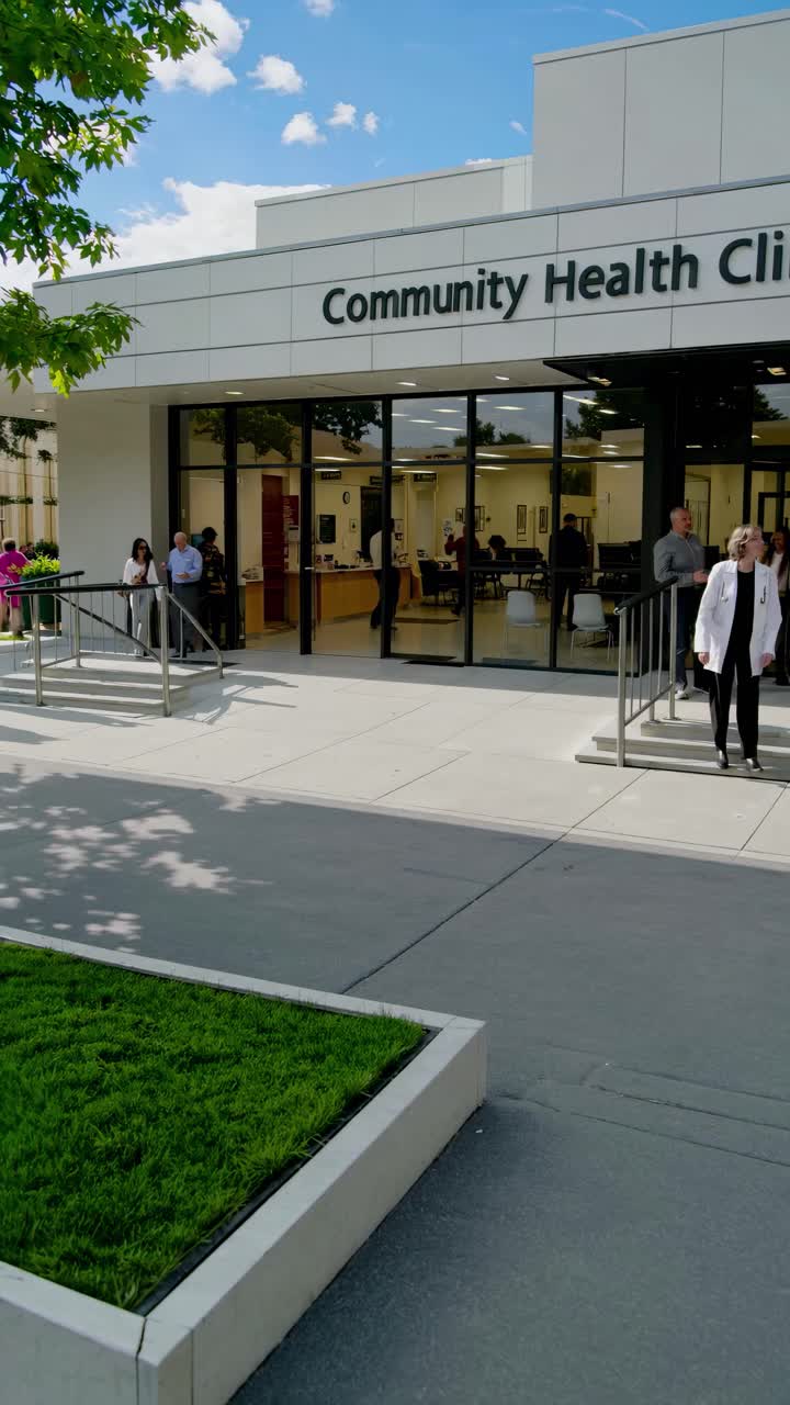 Plano de vídeo gran angular de la entrada de una clínica de salud moderna, capturando a gente entrando y saliendo