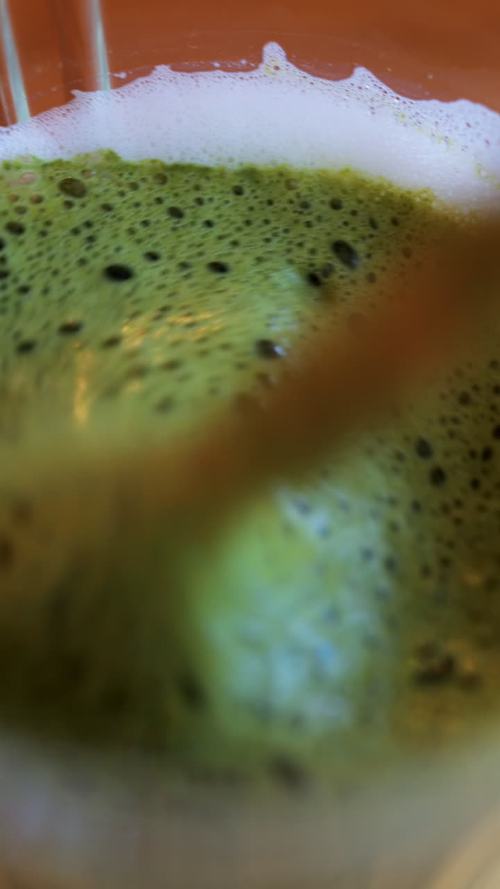 Close up of a spoon mixing in a matcha latte on a table at a cafe