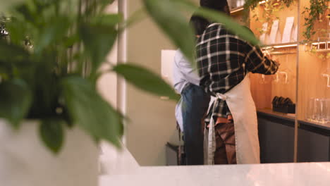 back view of two multiethnic waiters checking clean wine glasses hanging on rack