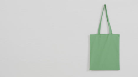 close up of green bag on white background, copy space, slow motion