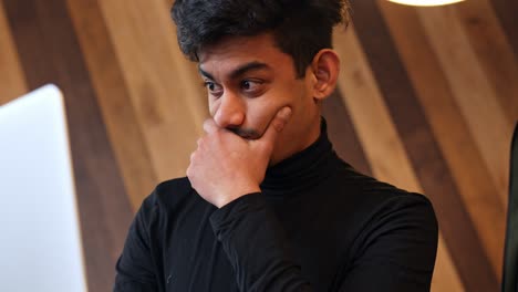 Thoughtful-designer-wearing-black-shirt-works-on-his-laptop-at-coffee-shop