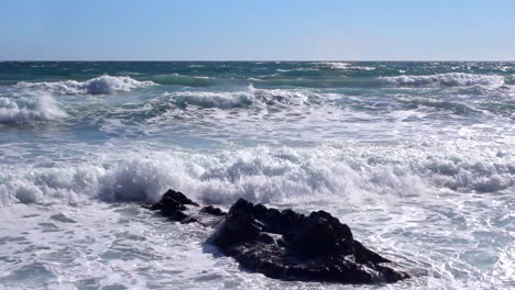 rough sea waves splashing on the rocks and on the beach