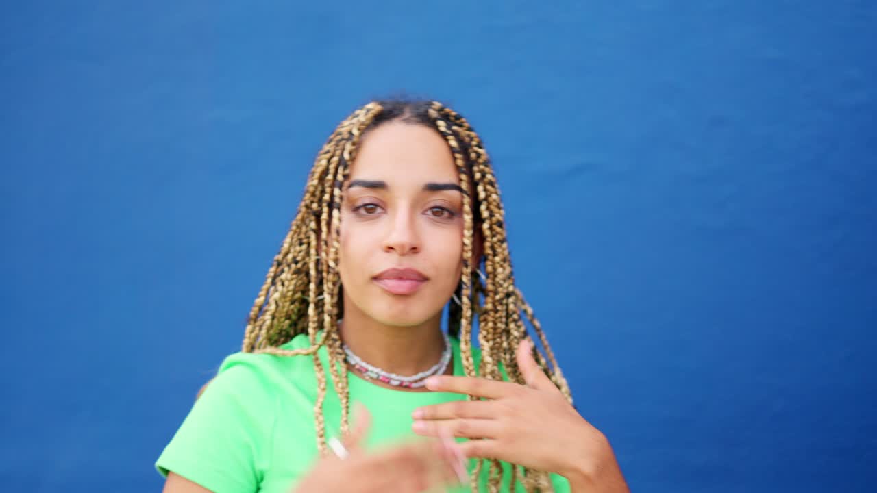 Latin woman smiling at camera next to a blue wall
