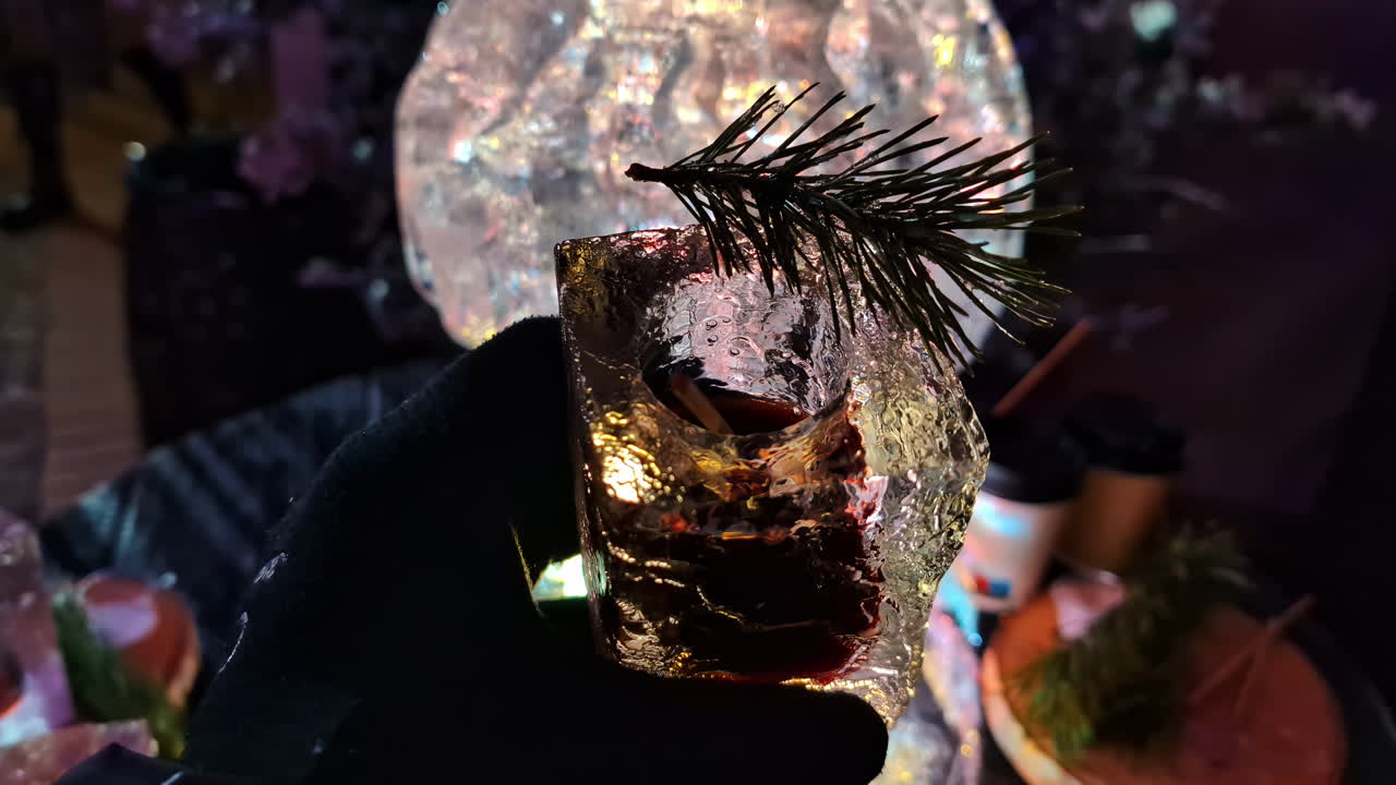 Close-up of a cocktail served in an ice glass with pine garnish at night during Jelgava Ice Festival