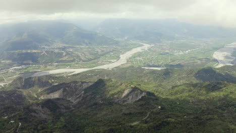 high altitude aerial view above dulan mountains through clouds to vast cultivated farmland , taitung valley