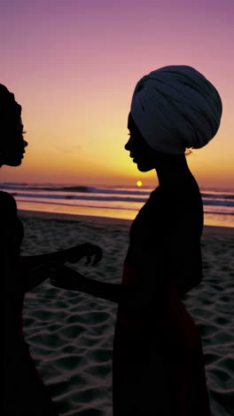 two women silhouetted on a beach at sunset