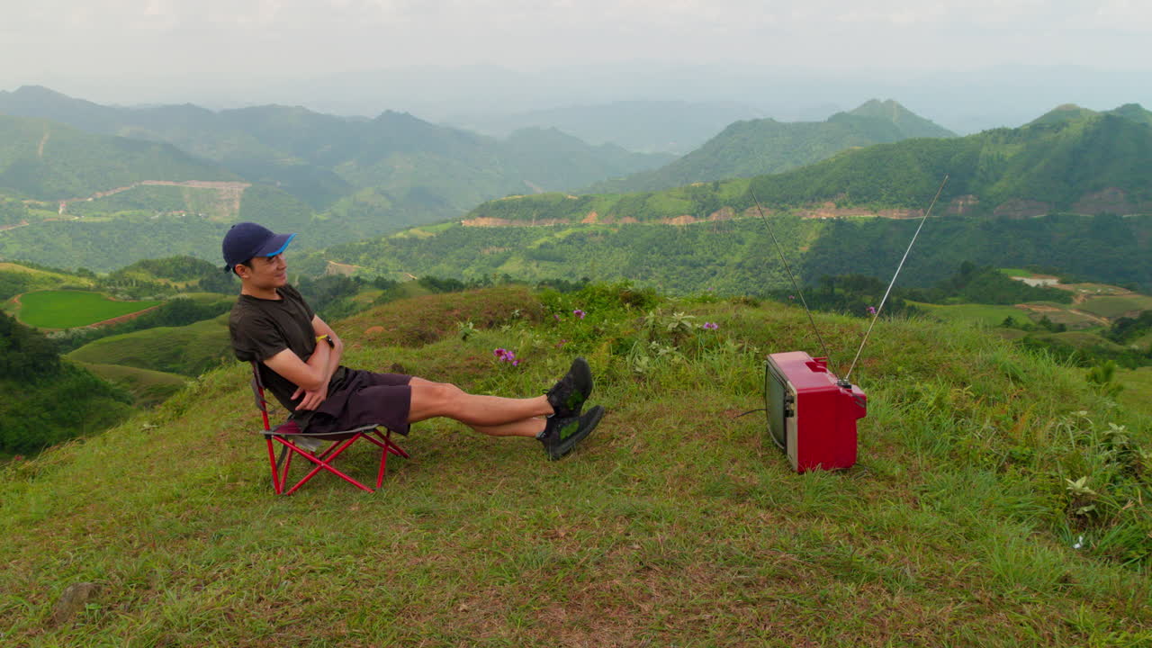 푸른 산 꼭대기에 있는  ⁇ 은 크리트 텔레비전을 보고 있는 편안한 남성