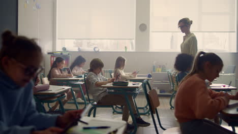 niños y niñas multiétnicos haciendo exámenes en línea con tabletas digitales en el aula