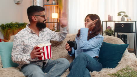 indian family couple man woman playing video joystick game laughing shouting with funny reactions