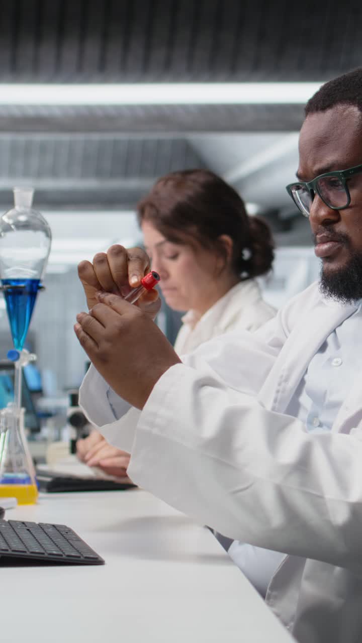 Vertical video Clinical laboratory technologist works on reviewing blood data on computer