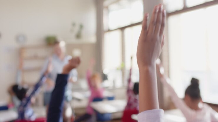 Na escola, alunos levantando as mãos na sala de aula, participando ativamente da aula.