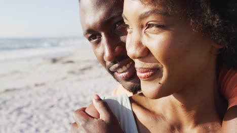 Sonriente-Pareja-Afroamericana-Abrazándose-Y-Mirando-Hacia-Otro-Lado-En-La-Playa-Soleada