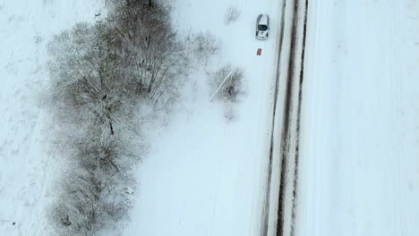 aerial flying over road in white snow on overcast day