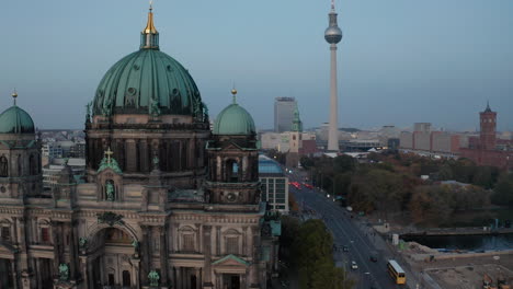 Forwards-fly-around-Berlin-cathedral-in-twilight-time.-Tall-TV-lookout-tower,-Fernsehturm,-in-background.-Berlin,-Germany