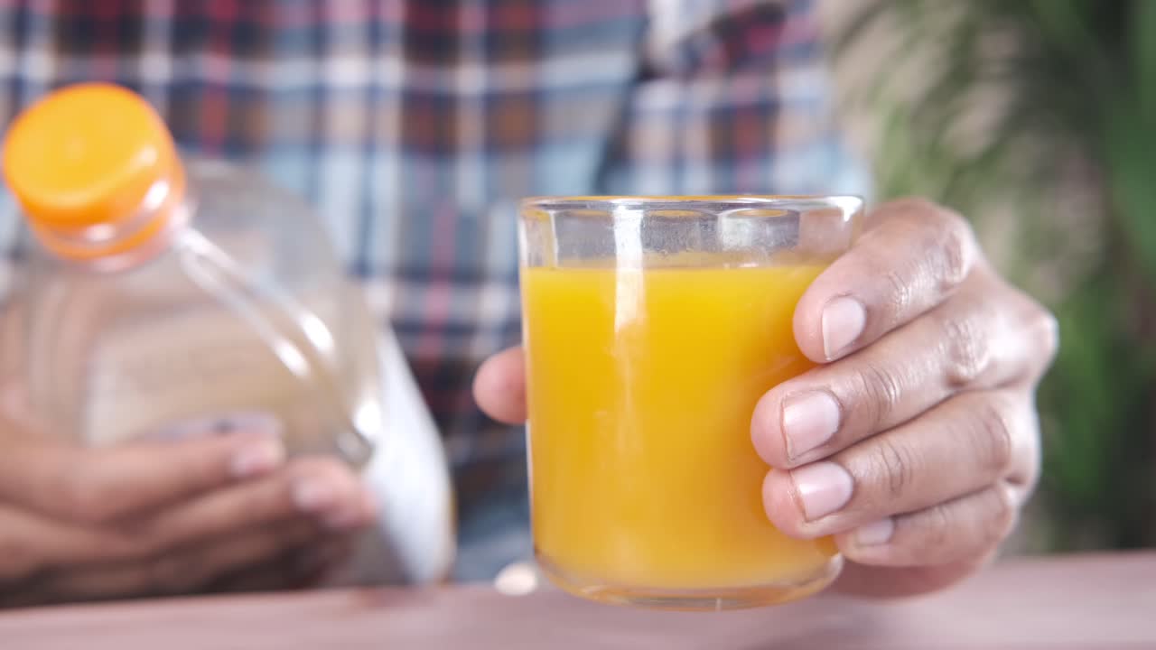 Person holding a glass of orange juice