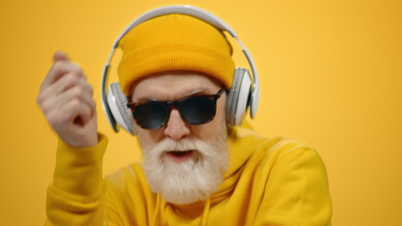 Anziano felice con le cuffie all'interno. Anziano che si muove a ritmo di musica in interni.