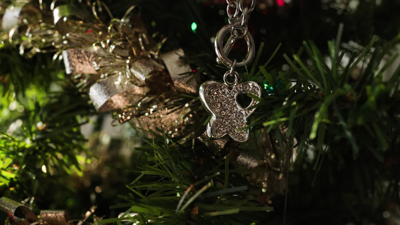 Butterfly Ornament on Faux Christmas Tree branch, handheld slow motion close up.