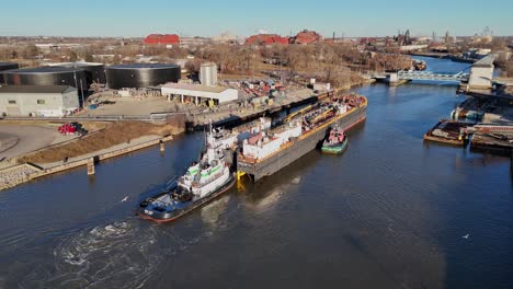 Industrial zone and massive barge moved by tugboats, aerial view