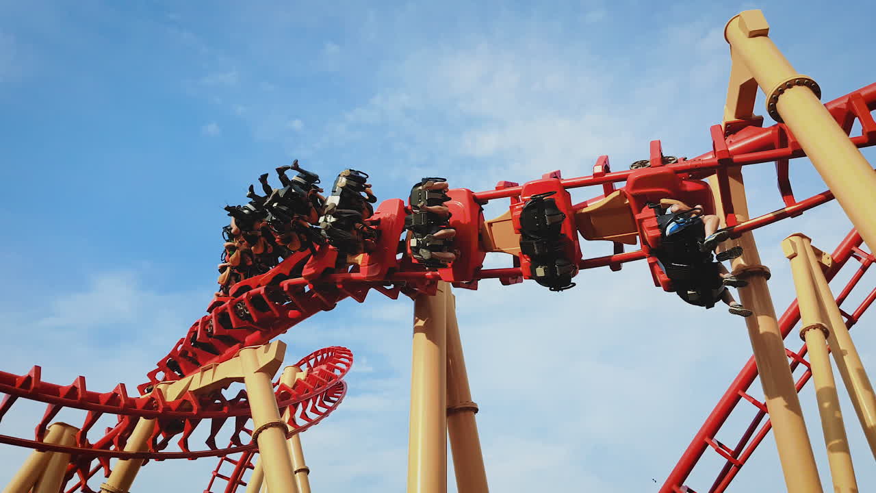 People riding twists and turns of a roller coaster at a theme park