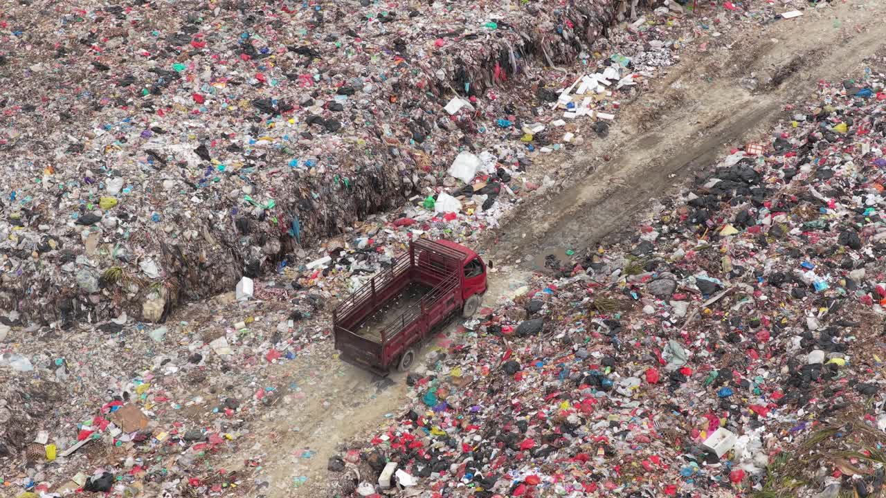 Roter Lastwagen fährt durch eine große Mülldeponie auf Bali