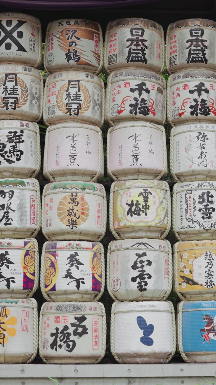 Vertical slow-motion panning along colorful and beautiful sake barrels at Meiji Jingu Shrine during the daytime in Yoyogi Park in Tokyo.