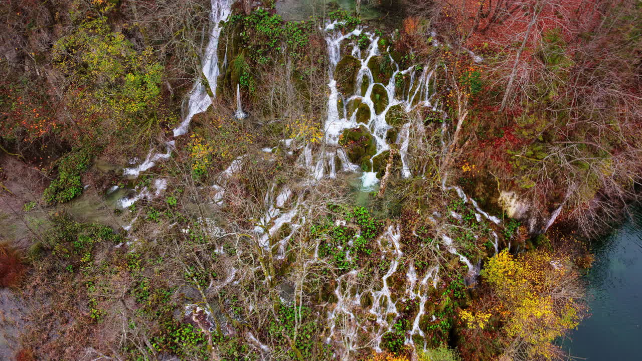 Vista aerea da drone di cascate a gradoni che scorrono su scogliere coperte di muschio e vegetazione lussureggiante nel Parco nazionale dei laghi di Plitvice, Croazia