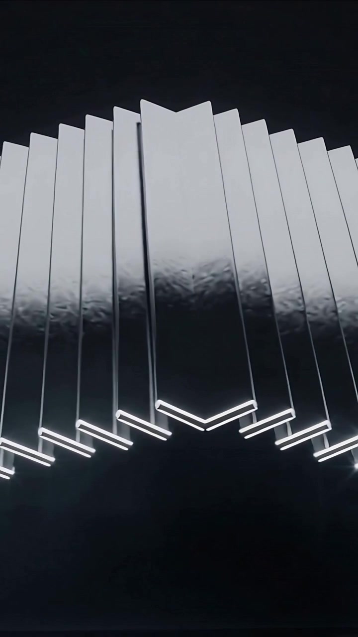 Video verticale: Alette metalliche motorizzate che ruotano formando una punta a chevron in uno studio buio, con LED che ne delineano i contorni.