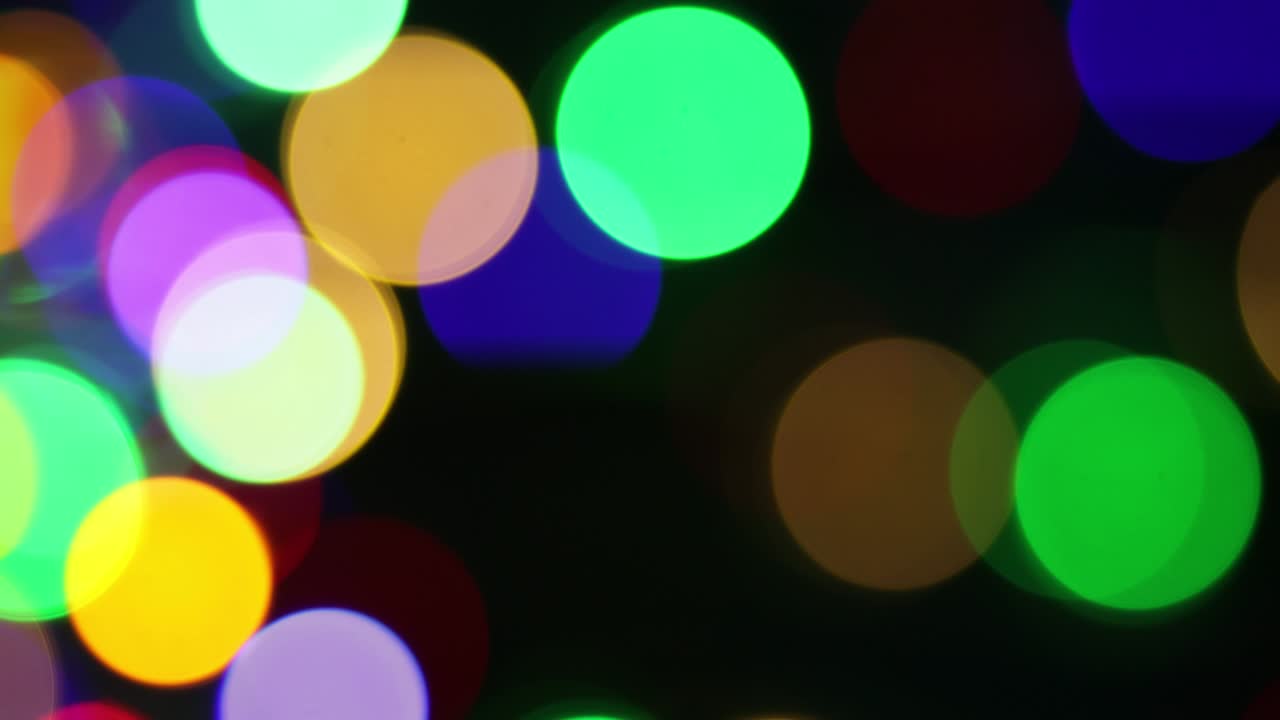 el fondo borroso de navidad. círculos de colores brillantes desenfocados luces de navidad video. la luz multicolor se filtra 4k imágenes en fondo negro