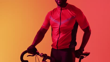 video of happy african american male cyclist looking at camera on neon orange lightning