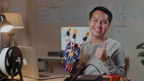 ingeniero feliz mostrando una mano robótica impresa en 3d