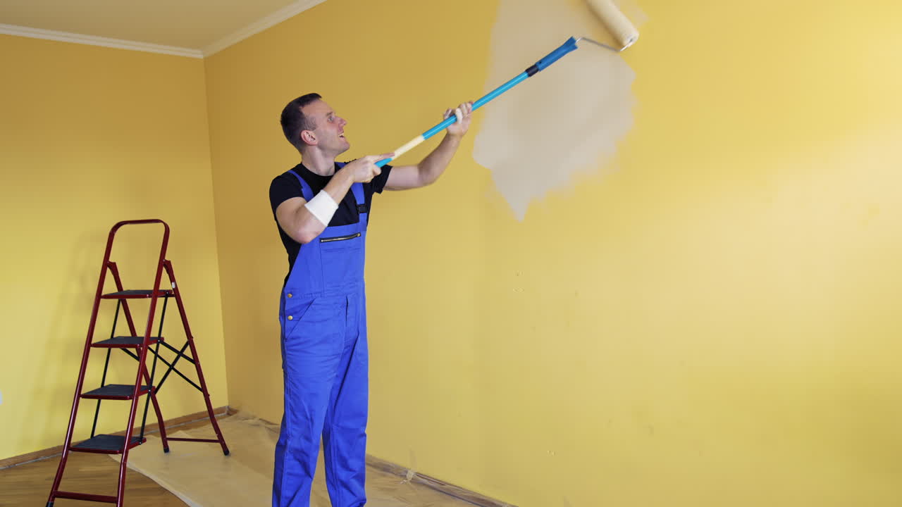 Man painting wall with paint roller. Young handsome man painting wall, redecorating room
