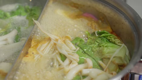 Boiling-Shabu-Shabu-Soup-In-Pot-With-Steam-And-Spoon-Stirring,-Close-Up