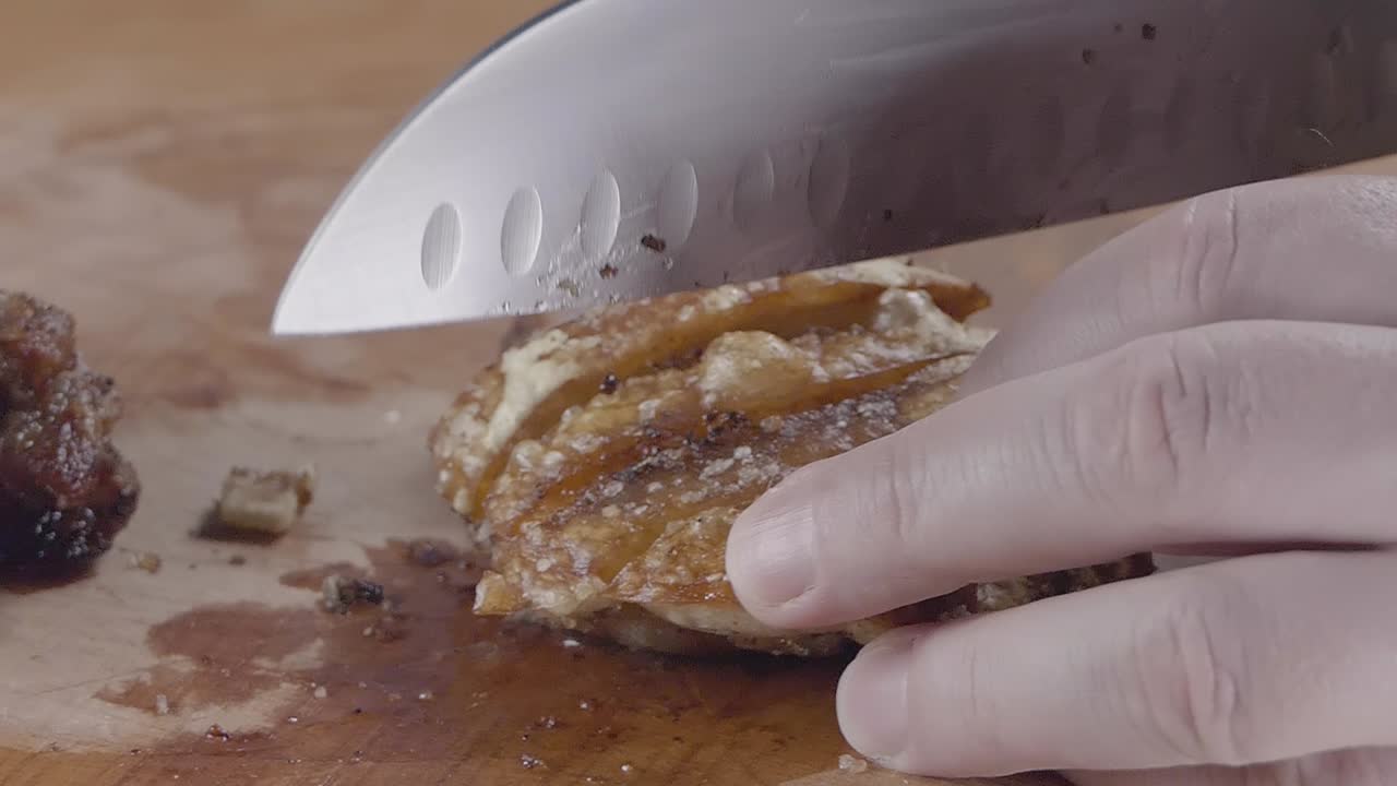 Slow Motion Shot of Cutting into Crispy Baked Pork Crackling on a Wooden Chopping Board