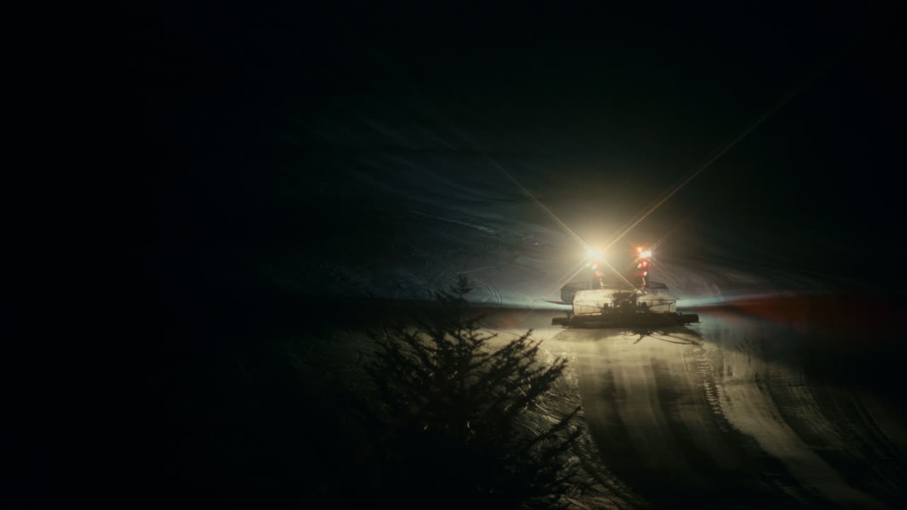 Snow groomer shaping fresh slopes at night in Japan