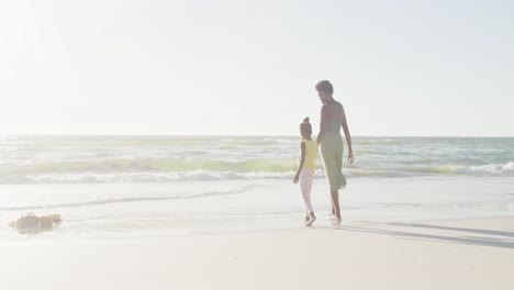 Happy-african-american-mother-and-daughter-walking-at-beach,-in-slow-motion,-with-copy-space