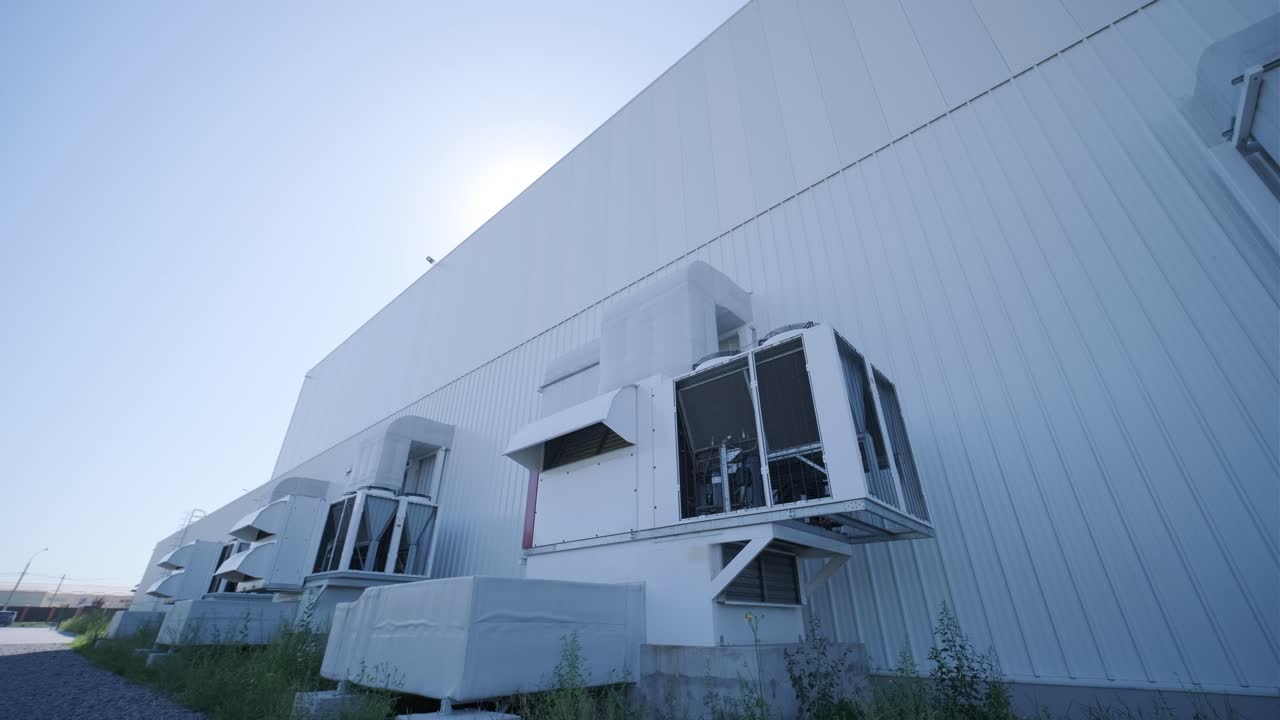 Large ventilation pipes on facade of commercial building. Outdoor split air conditioner units mounted on industrial building facade. Air conditioning system assembled on side of building