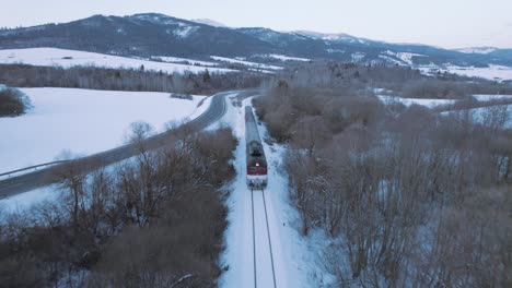 aerial-scenic-winter-snow-covered-landscape-train-driving-fast-through-remote-woodland-forest-in-tatra-national-park-in-Slovakia