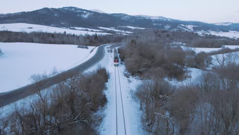 aerial scenic winter snow covered landscape train driving fast through remote woodland forest in tatra national park in slovakia